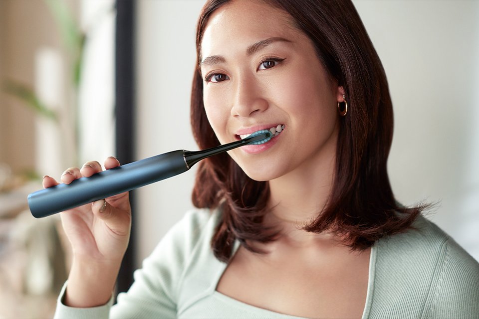 A woman using a Philips Sonicare electric toothbrush.