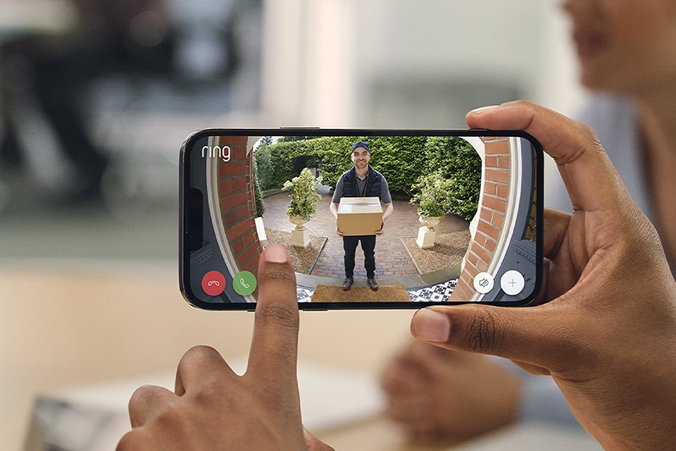 Someone holding a phone displaying security camera footage of a doorstep.
