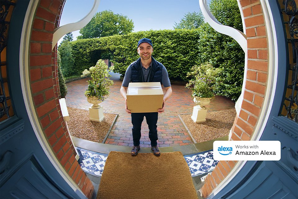 A webcam view of a man holding a parcel at a doorstep.