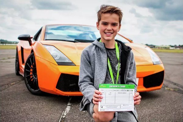 A child standing by a race car.
