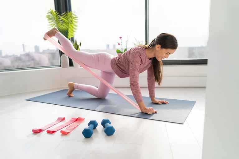 A woman exercising with a resistance band on a yoga mat.