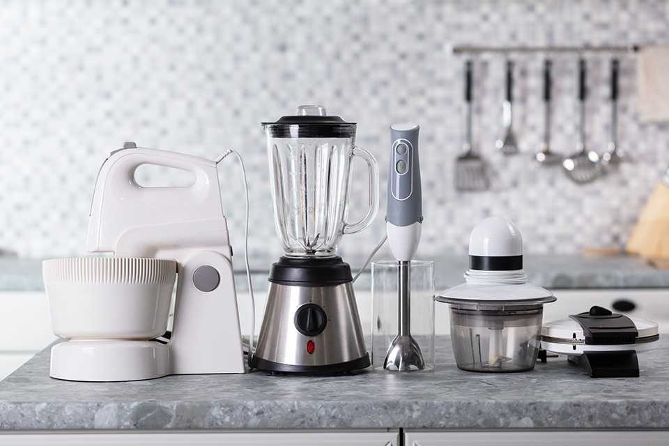 Small kitchen appliances lined up on counter top.