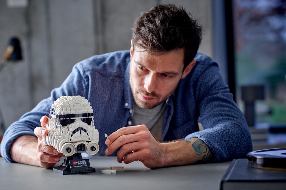A man in a grey jersey puts the finishing touches to a LEGO® Star Wars™ model spaceship