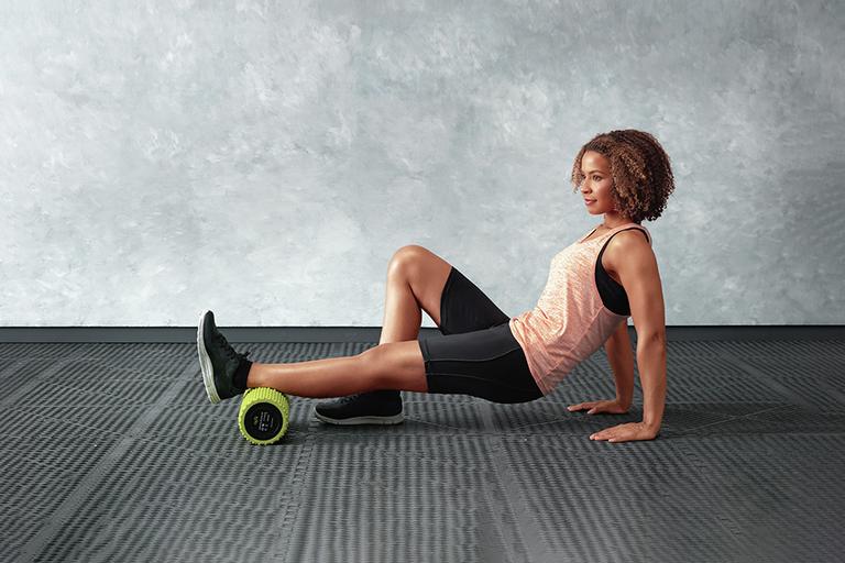 A woman using a foam roller for her leg exercise.