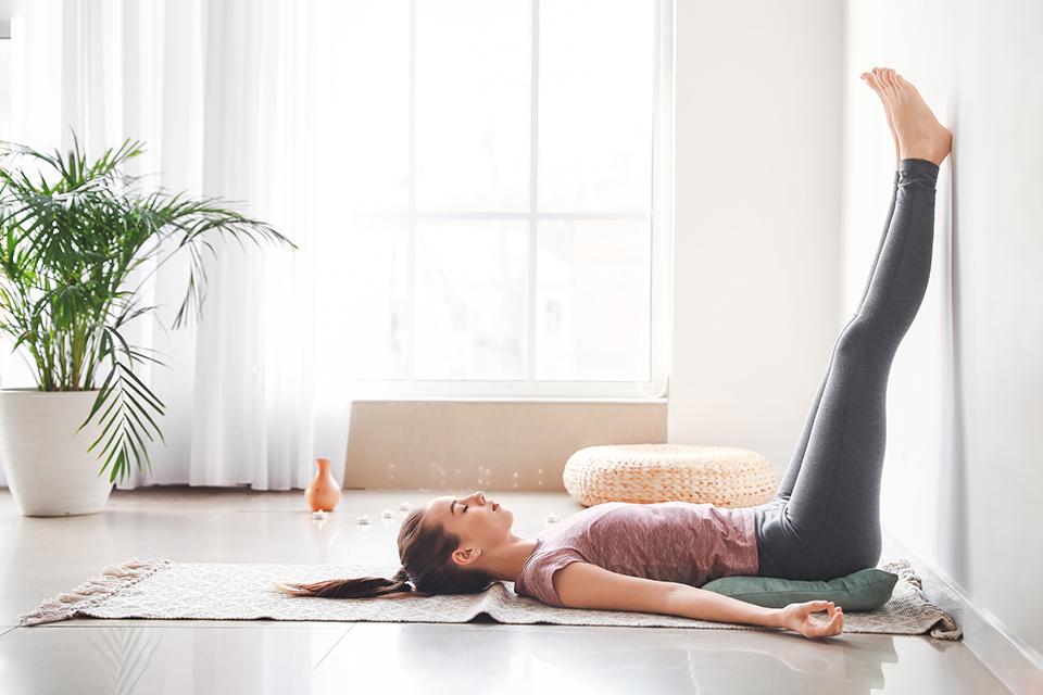 A woman doing a leg-up-the-wall pose while practicing yoga at home.