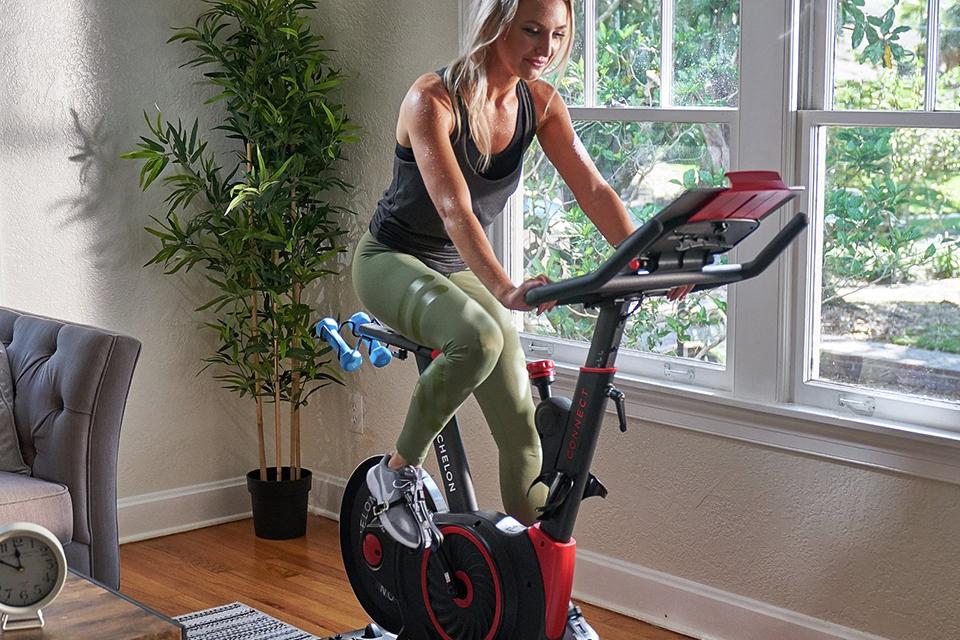 A woman using an Echelon Connect 3 exercise bike in her home gym.
