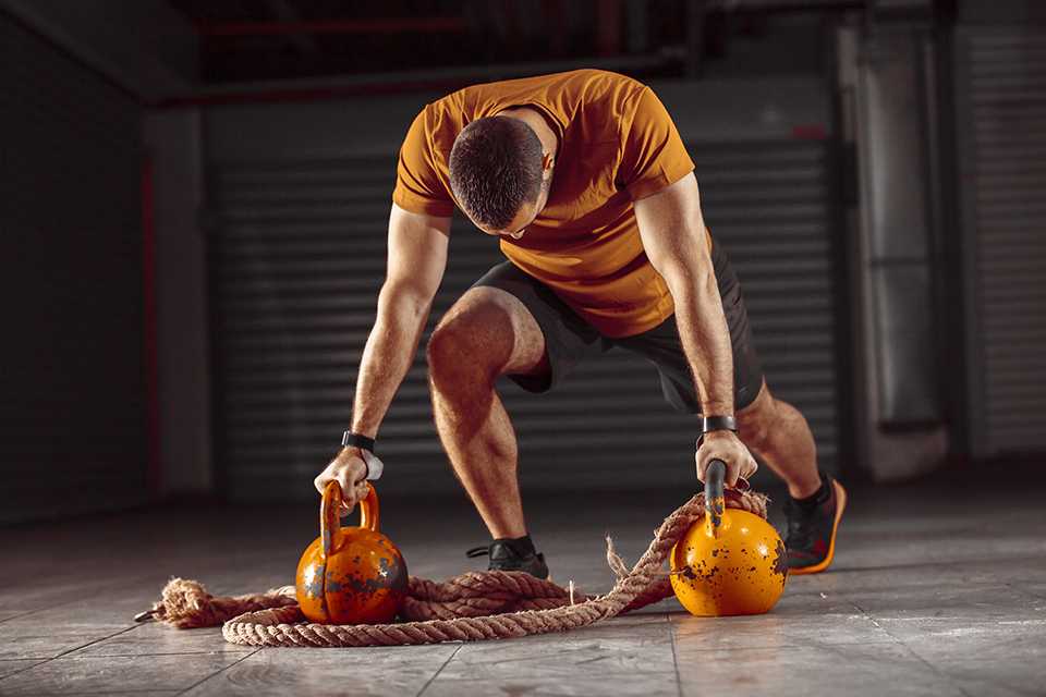 A man exercising using kettlebells in a garage gym.