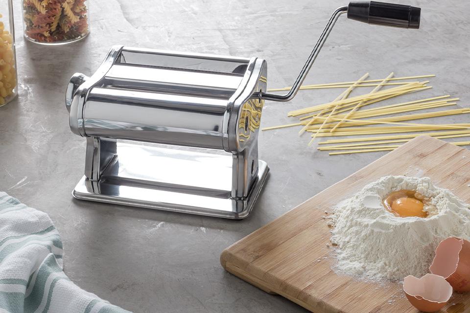 The Argos Home pasta maker on a kitchen counter with egg and flour.