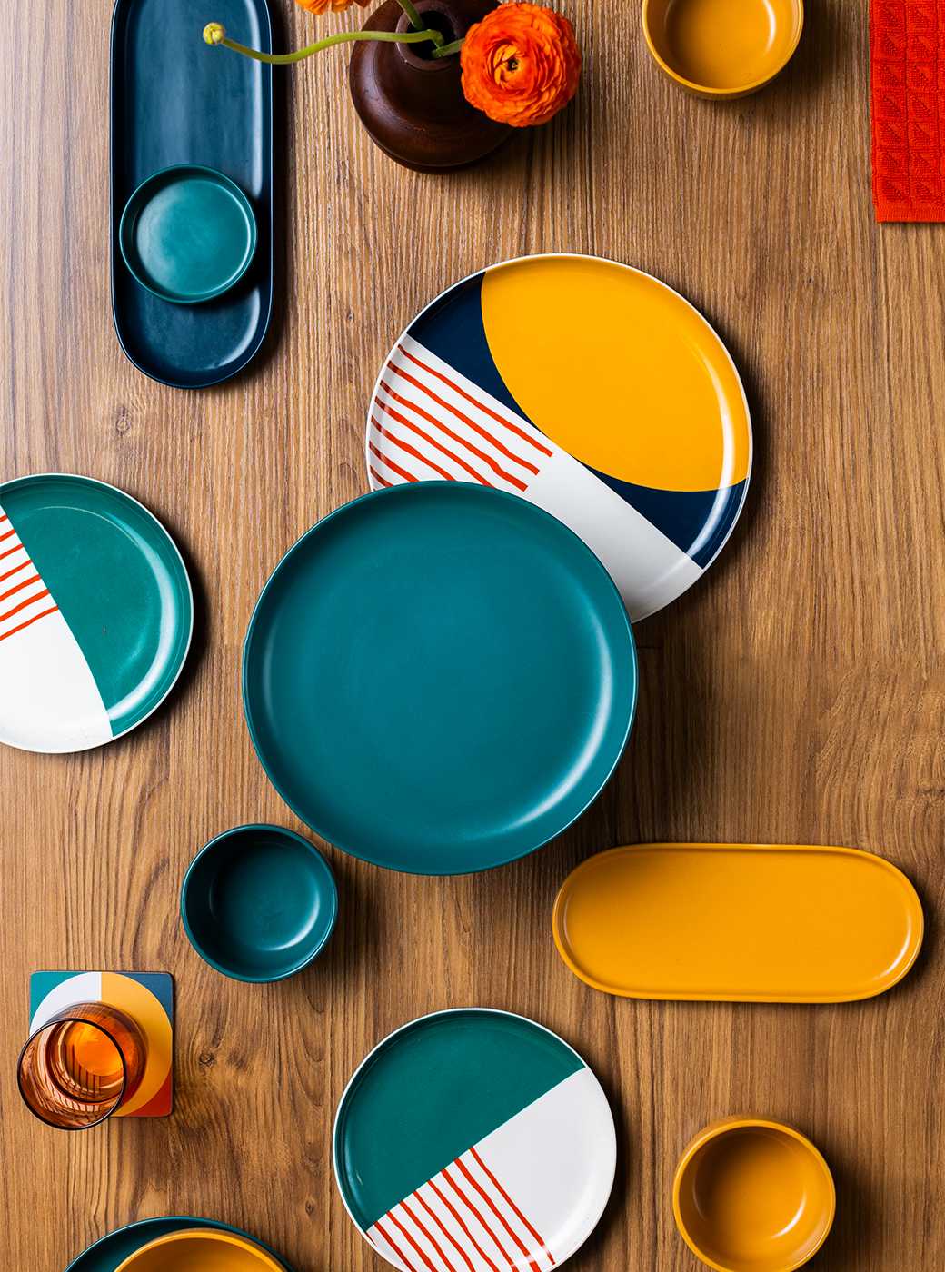 Wooden dining room table with colorful tableware.