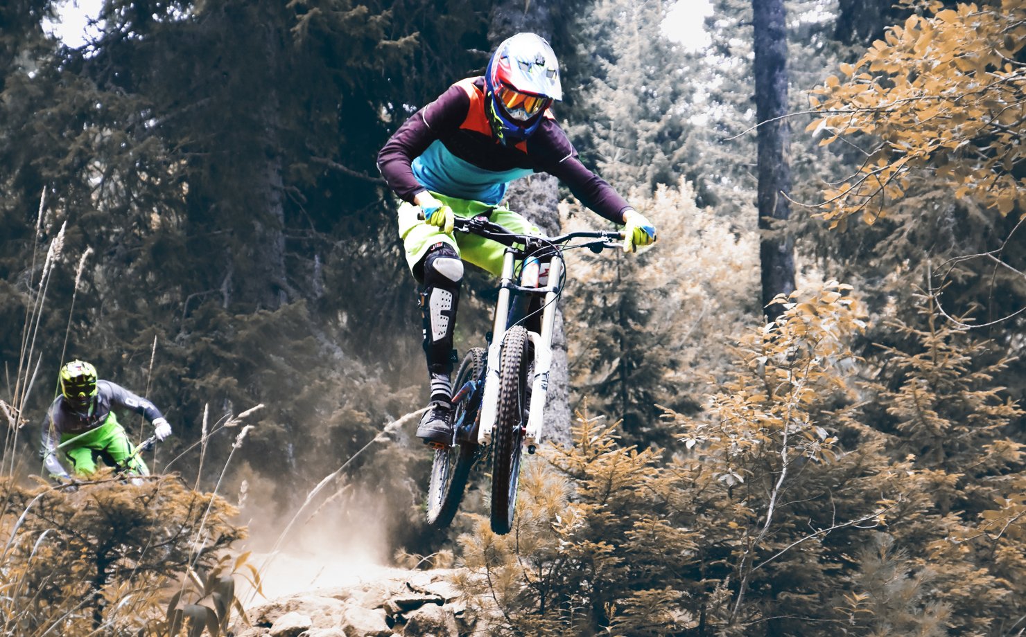 A person in a helmet performing stunts on the bike in a forest.