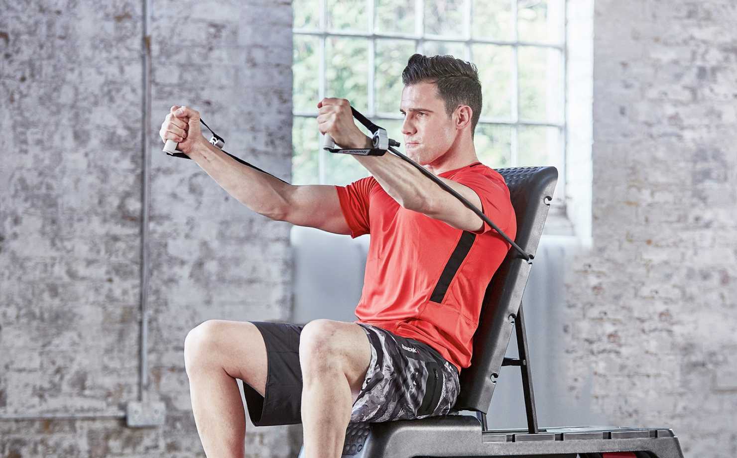 A man doing a cable chest fly on a workout bench.