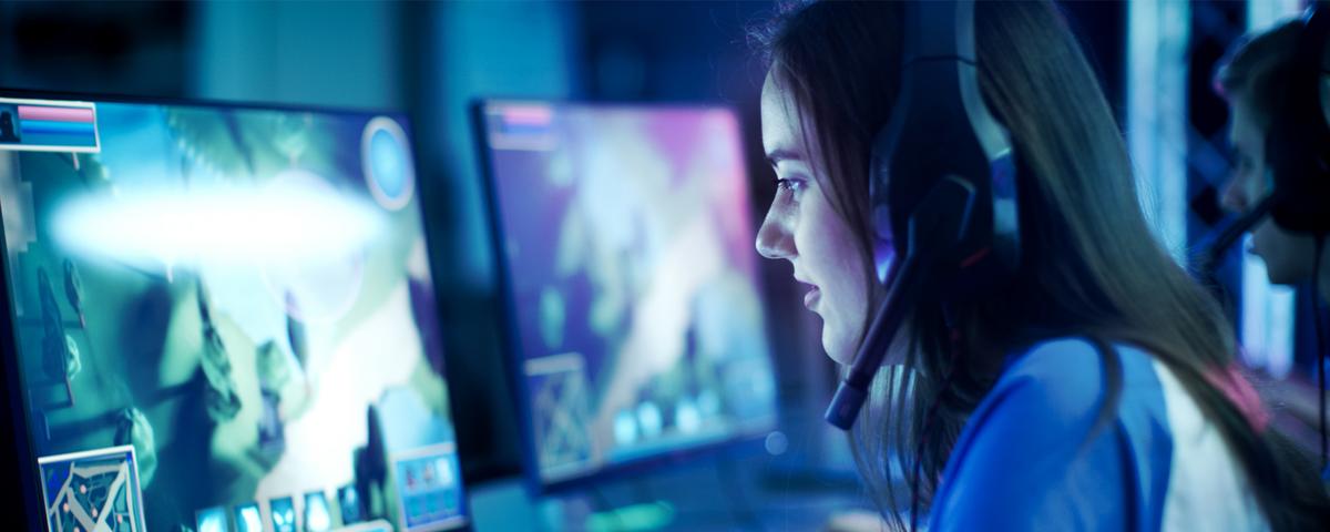 A woman wears a gaming headset with playing on her PC.