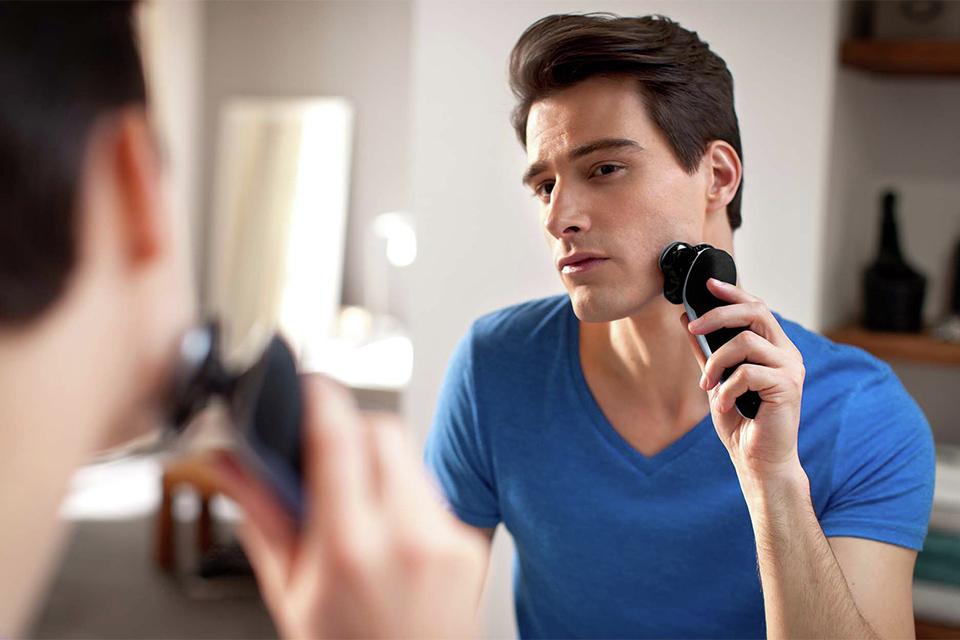 A man shaving in his bathroom mirror.