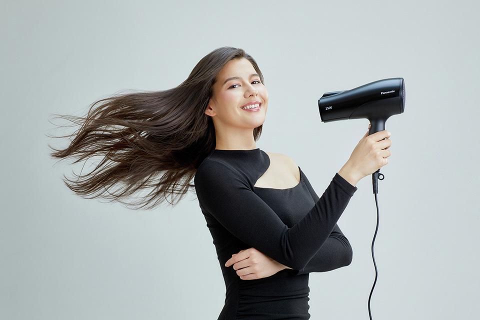 A lady blow drying her long brown hair.