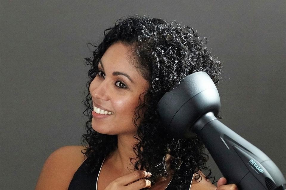 A woman using a diffuser on her curly hair.