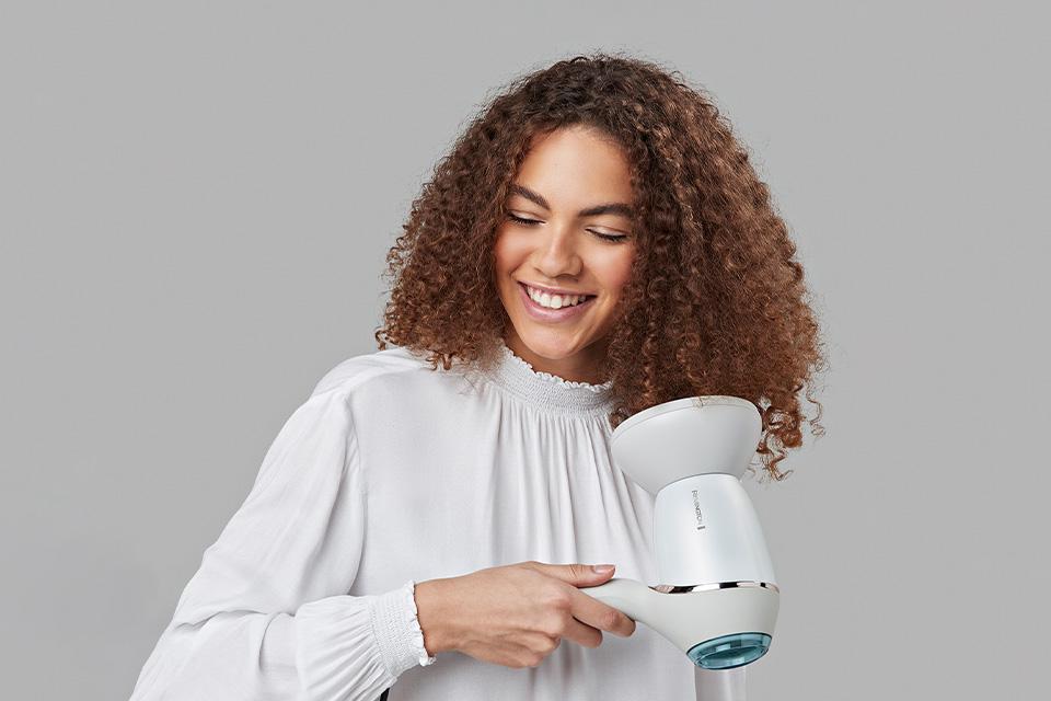 A lady using the diffuser on her curls.