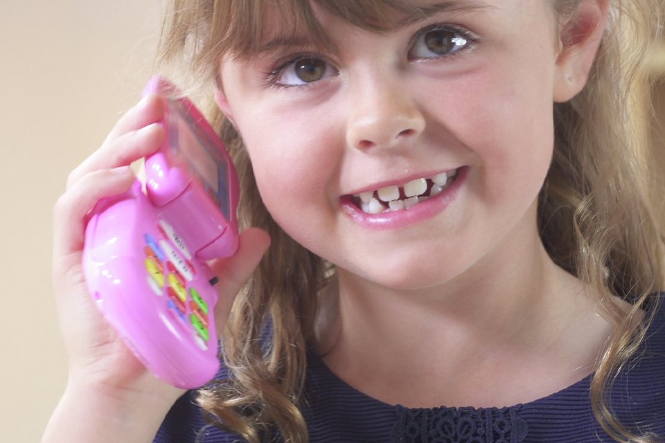 A girl playing with a Peppa Pig Flip & Learn Phone.