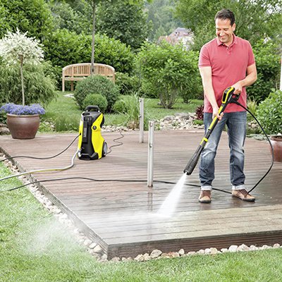 A man using a pressure washer in his garden.