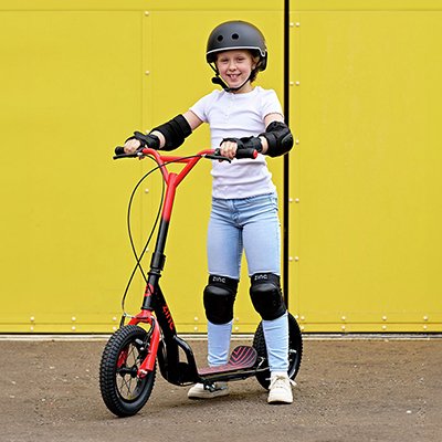 A young boy with a helmet and elbow and knee pads on a scooter.