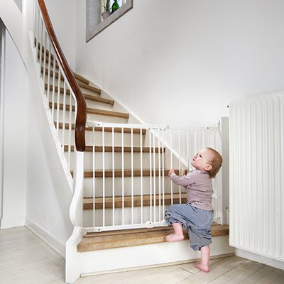A baby next to a baby gate in front of some stairs.