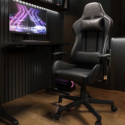 A black gaming chair next to a PC on a desk.