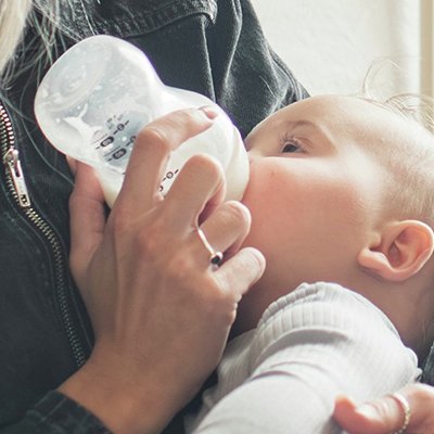 A mother feeding her baby with a milk bottle.