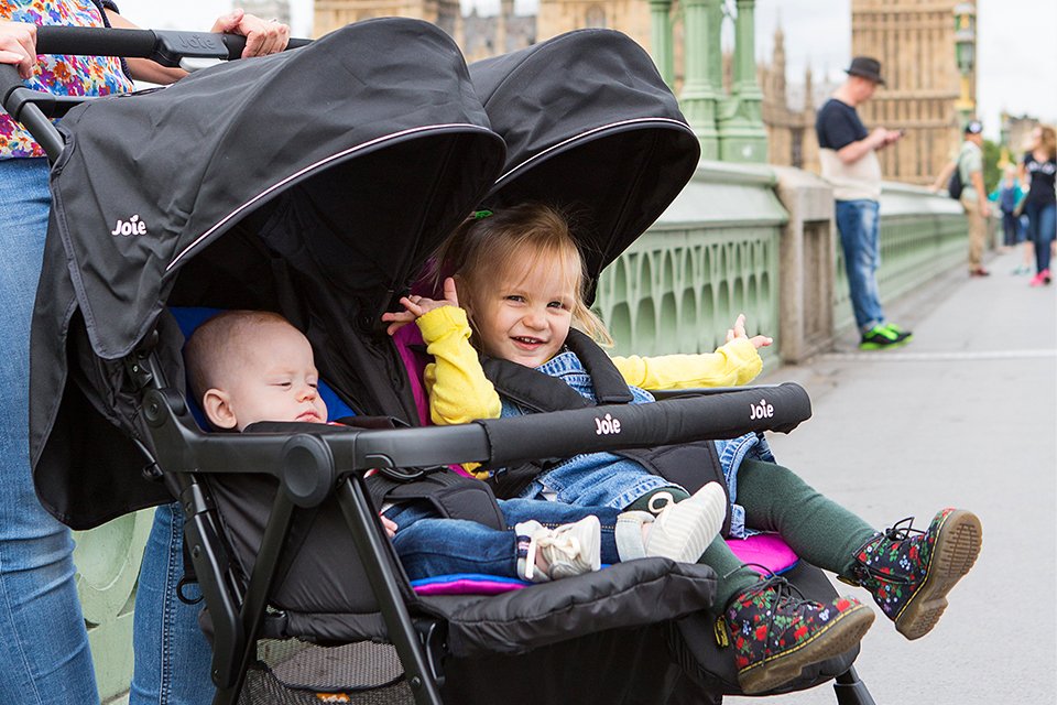 A mother pushing her two children in the Joie aire™ twin stroller. 