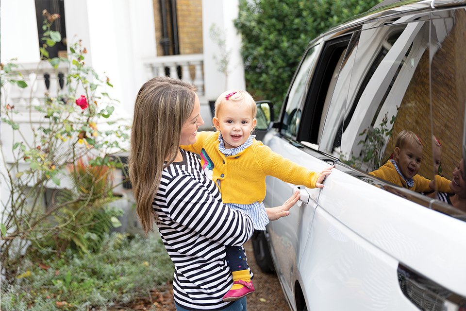 A mother getting her baby ready for a car journey in a Joie car seat. 