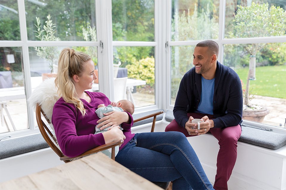 A young couple relaxing at home with their new-born fast asleep.