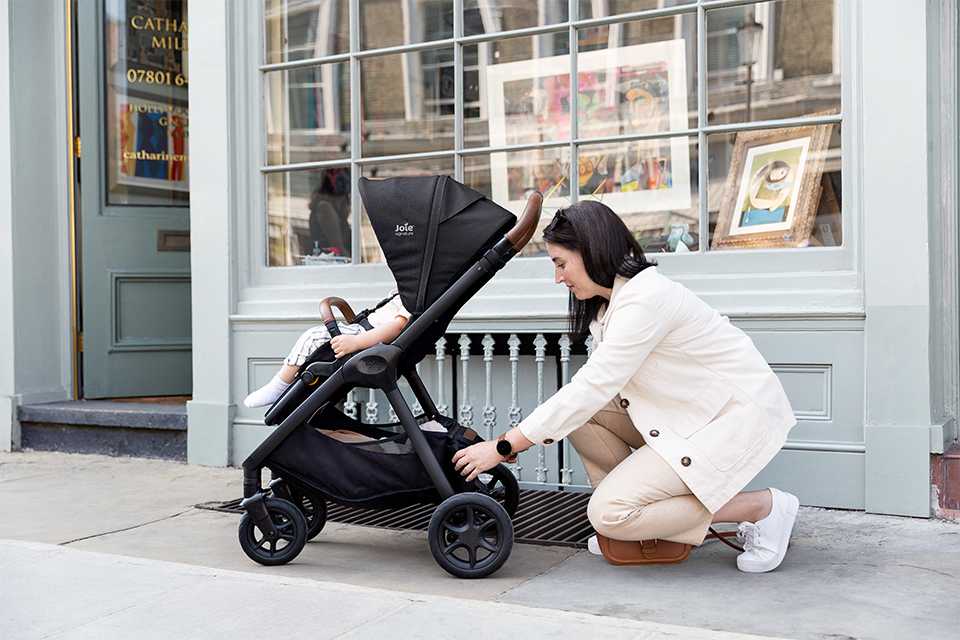 Baby happy in the Joie signature finiti™ while mum is looking in the stroller's storage basket.