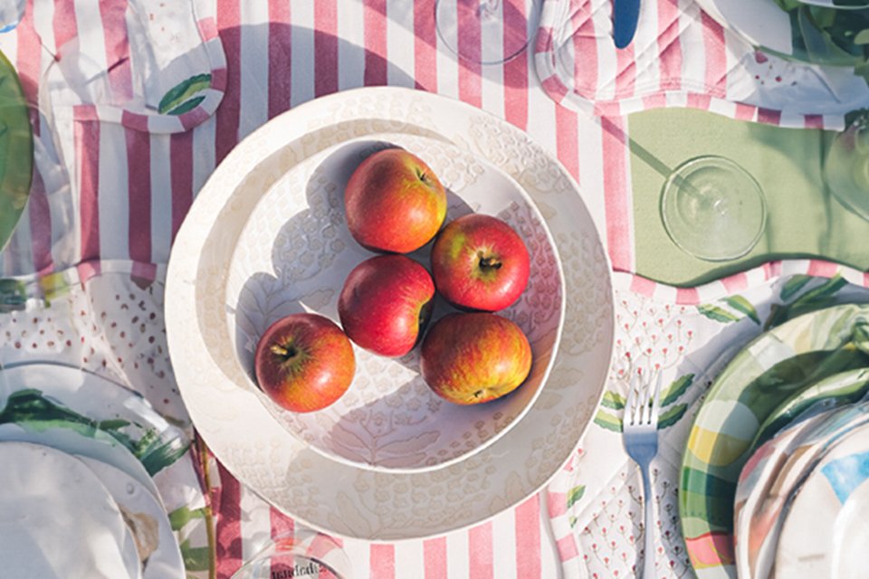 A Habitat x Sanderson & National Trust Bellis pasta bowl with fruit on a table.