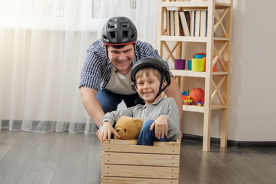 A father-son duo playing with a toy crate with wheels.