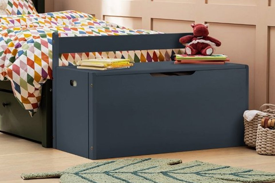 A grey wooden storage box in a kids' bedroom.