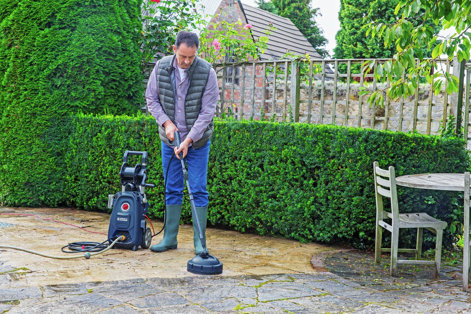 man pressure washing patio
