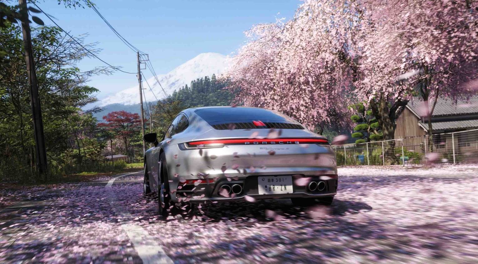 screenshot of a silver Porsche driving through cherry blossom covered Japanese streets from Forza Horizon 6.