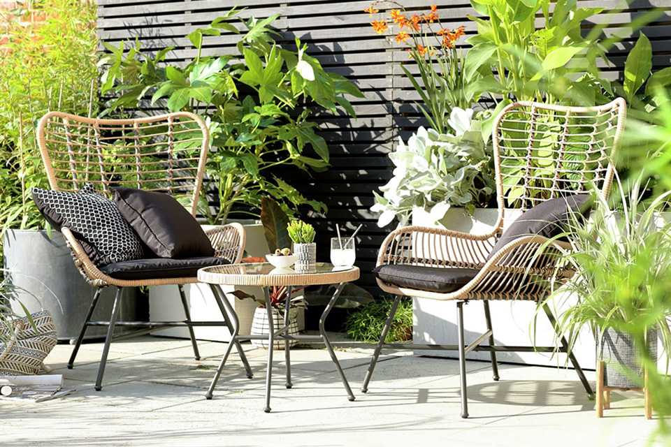 A garden two seater bamboo chair and coffee table set paired with outdoor black cushions.