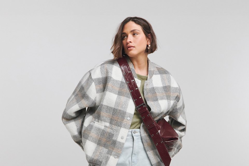 Woman in white and grey jacket with bag.