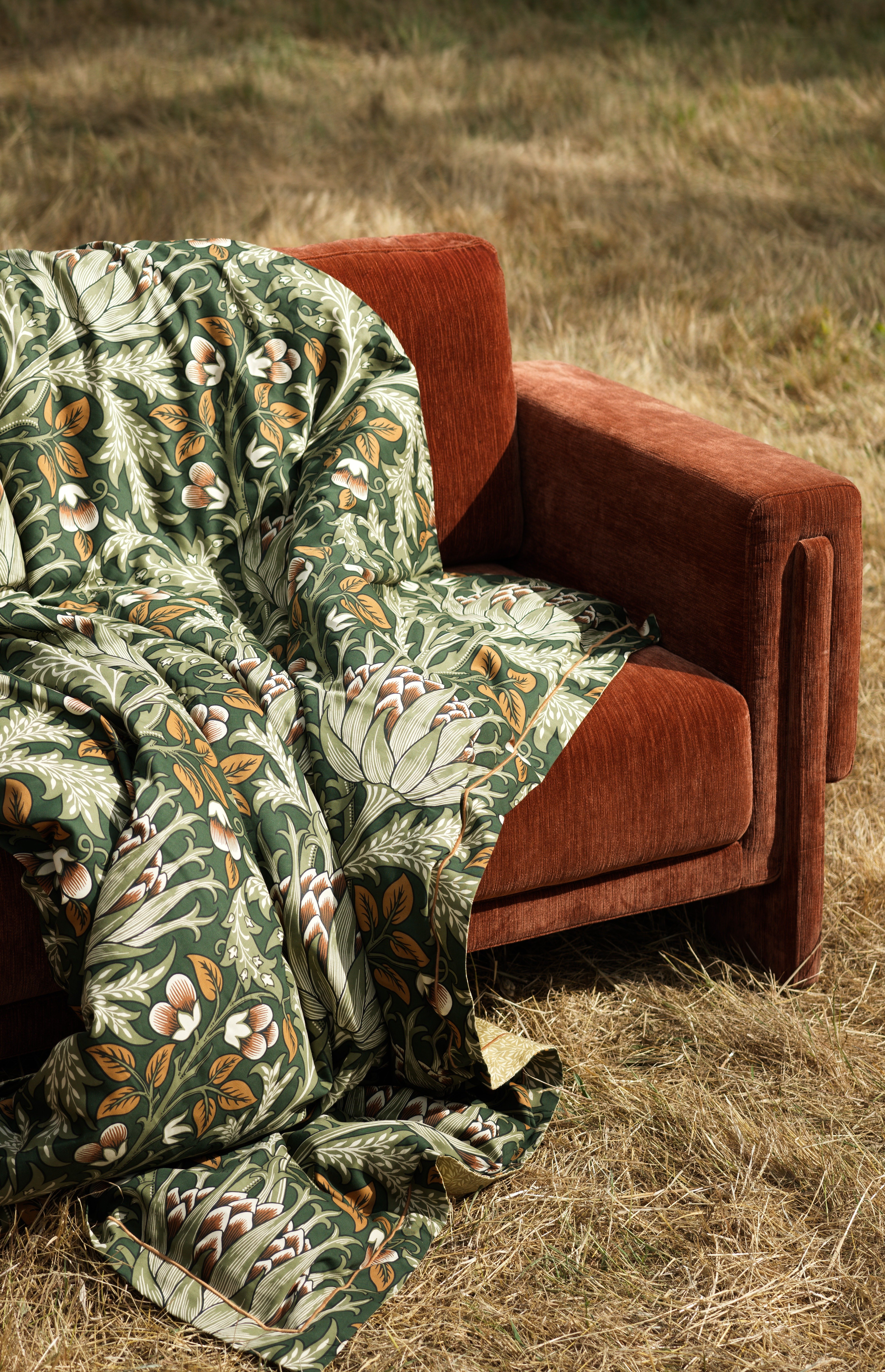 orange velvet sofa in field with botanical green print throw draped over sofa
