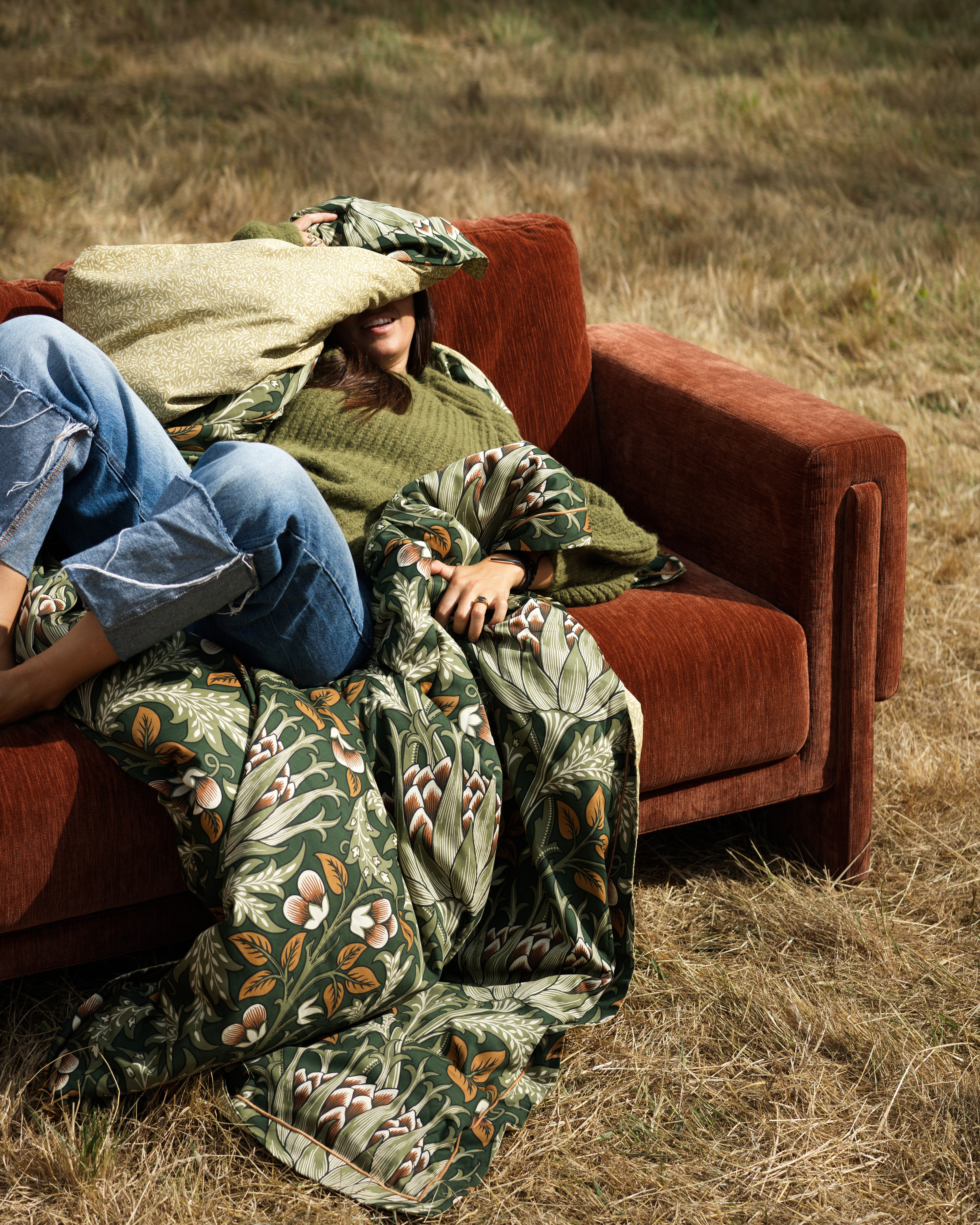 person on sofa in field in orange colour with blankets and cushions