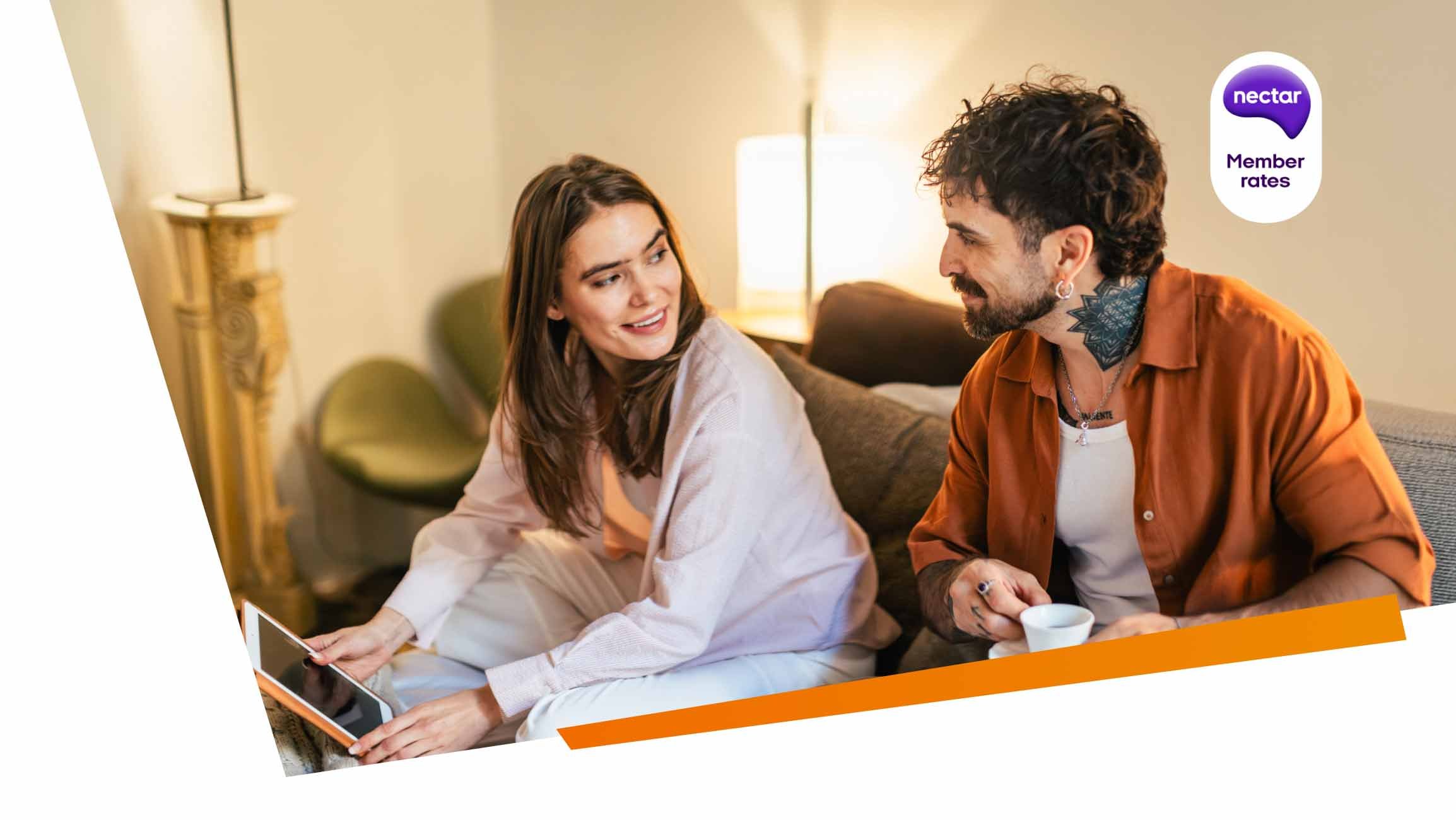 Two people using a tablet on a sofa