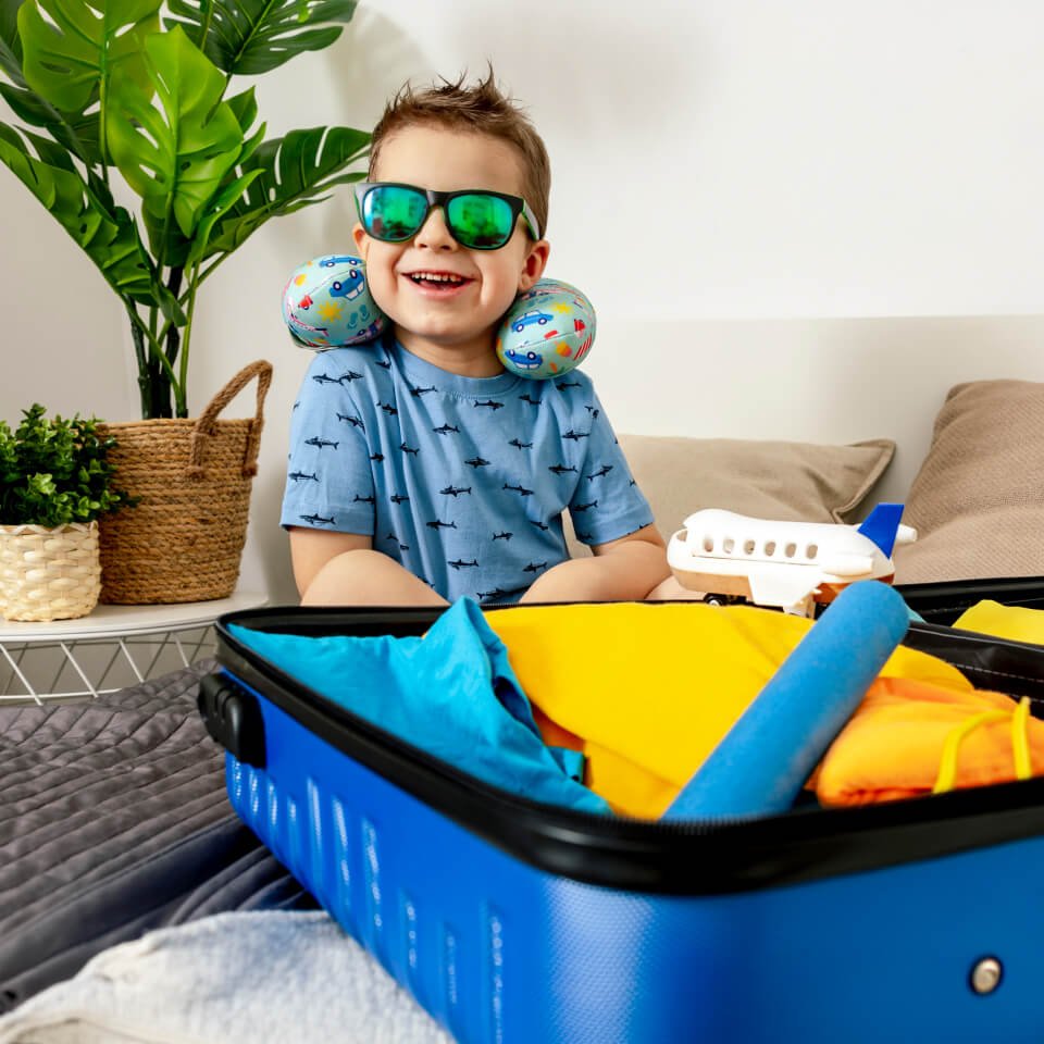 Child wearing sunglasses beside a suitcase