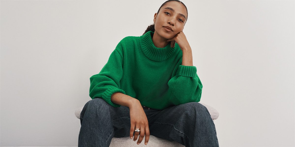 Women wearing green knitted jumper and barrel leg jeans.