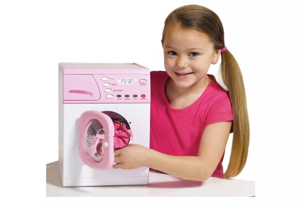 A girl playing with a toy washing machine.
