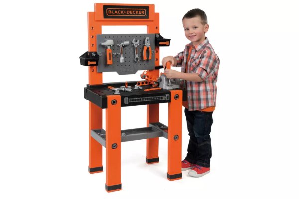 A boy playing with a pretend work bench with tools.