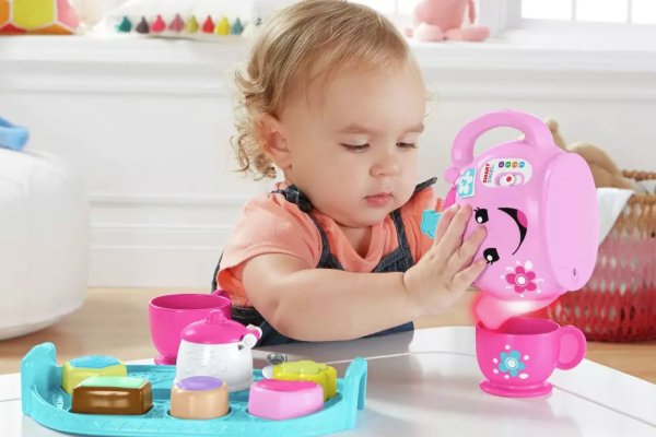 A girl playing with a toy tea set.