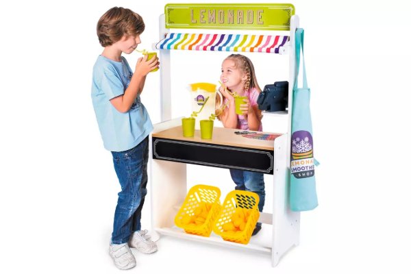Two children playing with a lemonade stand set up.
