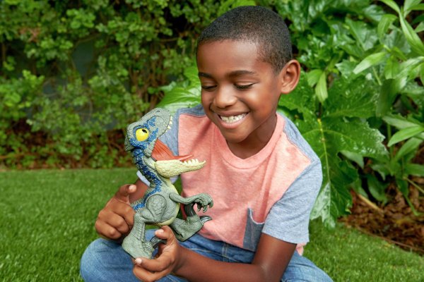 A boy playing with a dinosaur toy in a garden.