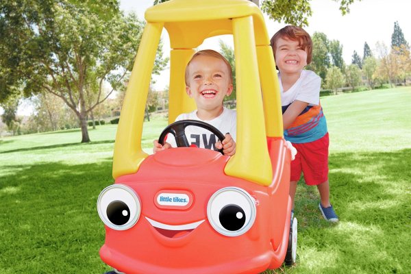 Two children playing with a toy ride-on car.