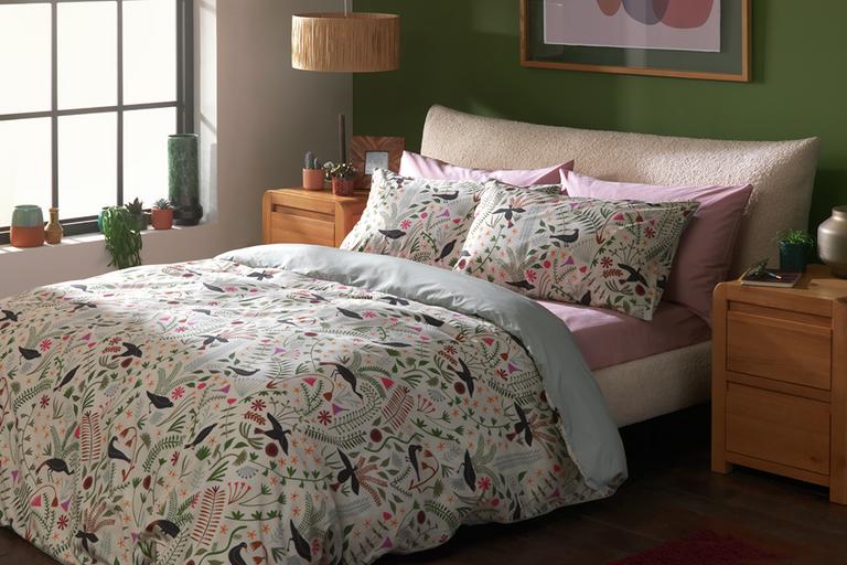 A Habitat Folktale floral print double bedding set and pillows on a bed.