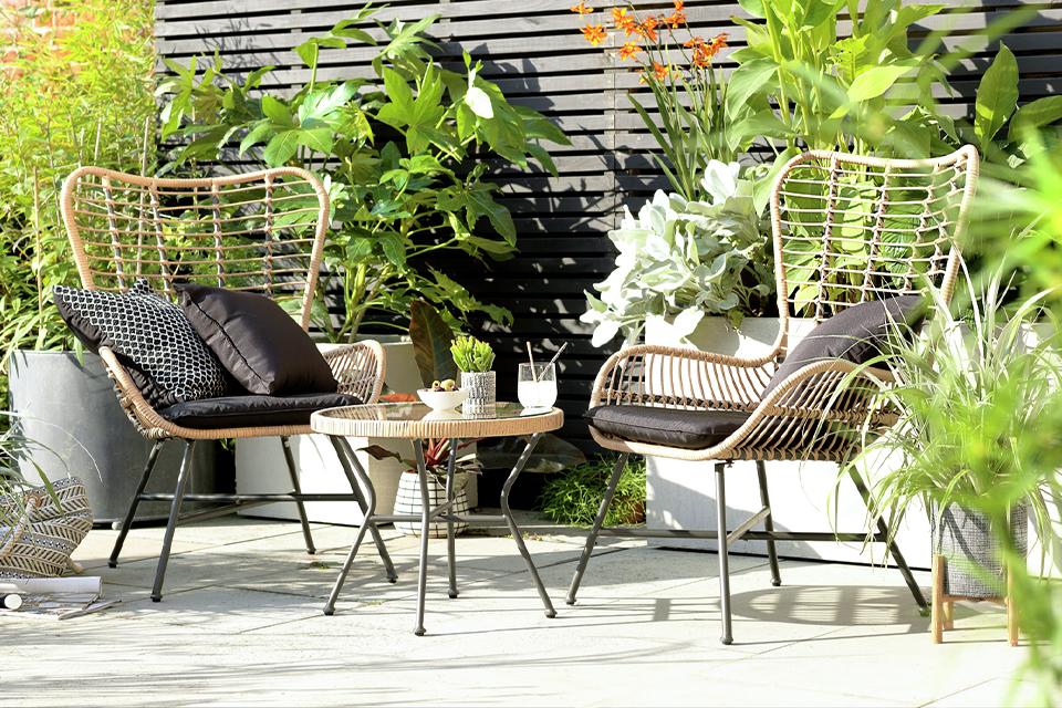 A Habitat 2 seater bamboo bistro set in natural finish with black cushions.